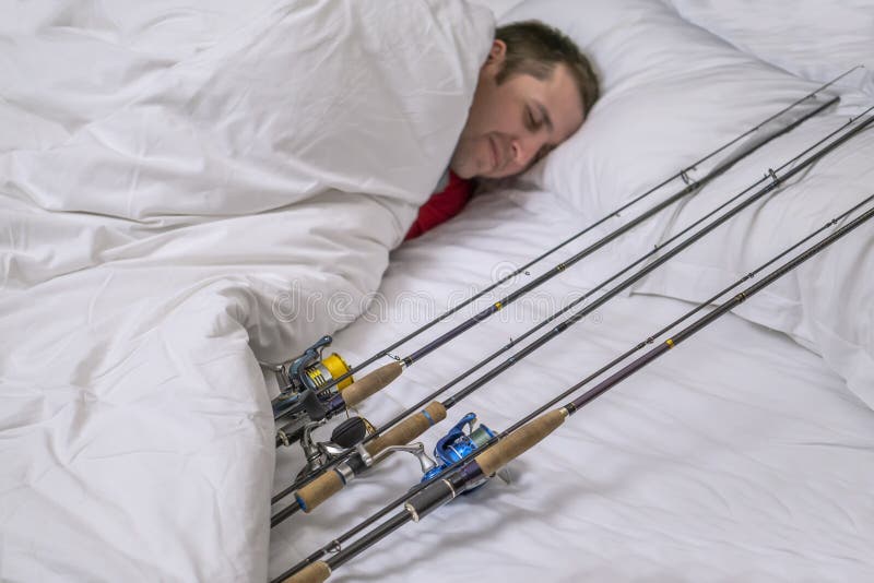 Sleeping fisherman in bed with fishing tackles. Think and dream about big fish. Sleeping fisherman in bed with fishing tackles. Think and dream about big fish