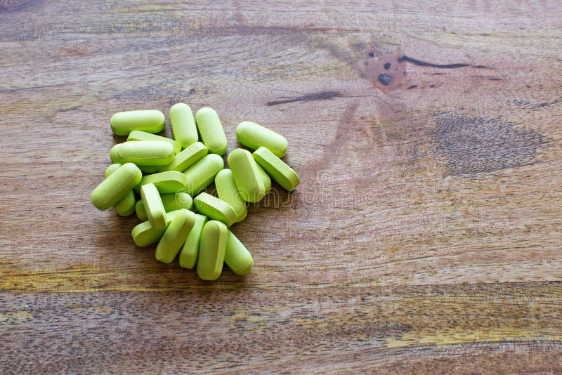 Green calcium pills over aged wood board. Green calcium pills over aged wood board