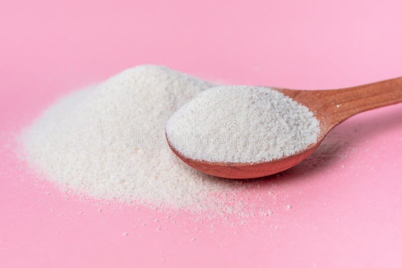 Natural collagen powder and spoon over pink background, concept of cosmetic skin care. Natural collagen powder and spoon over pink background, concept of cosmetic skin care