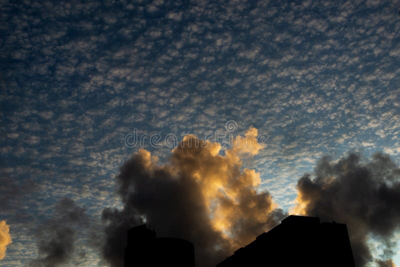 Pôr do sol dramático e bonito com nuvens coloridas e parte de edifícios residenciais na silhueta imagem de stock royalty free