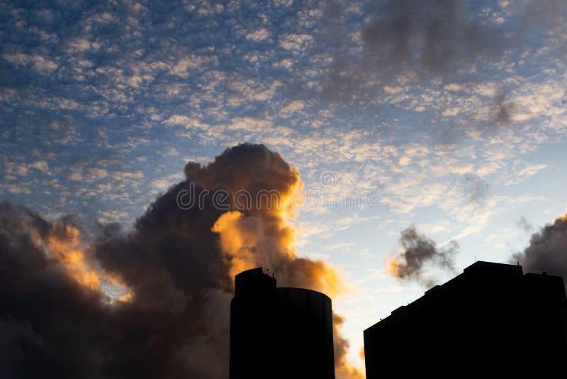 Pôr do sol dramático e bonito com nuvens coloridas e parte de edifícios residenciais na silhueta foto de stock