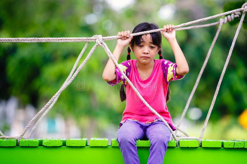 Crying little asian girl sitting alone on a playground, Outdoor. Crying little asian girl sitting alone on a playground, Outdoor