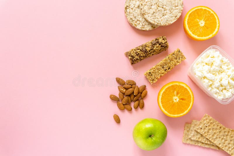 Płaskie leżakowanie zdrowych przekąsek. owoce muesli krąży chleb chrupki i orzechy na różowym tle do tekstu obraz stock