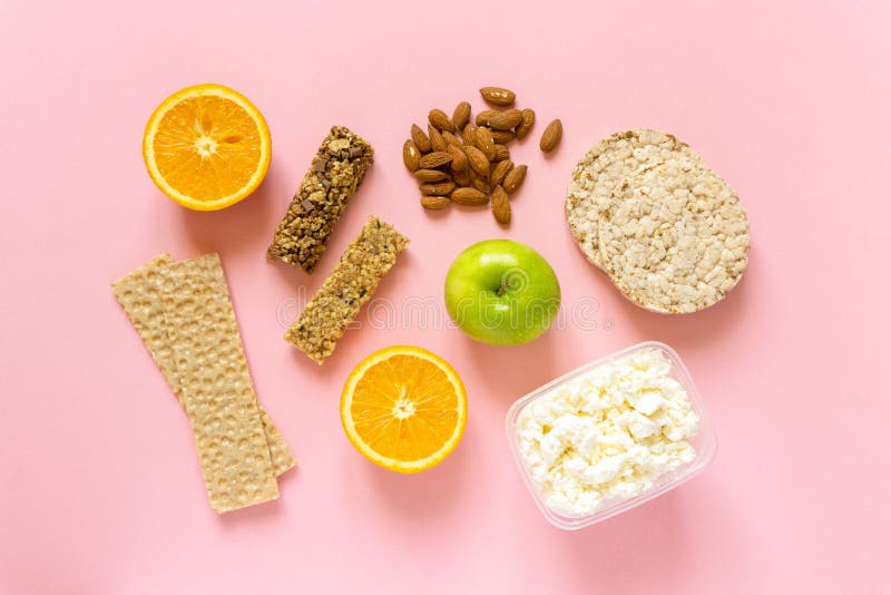 Płaskie leżakowanie zdrowych przekąsek. owoce muesli krąży chleb chrupki i orzechy na różowym tle widok z góry zdjęcia stock