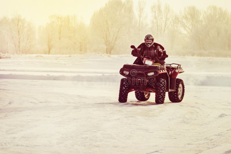 Quad bike driver riding over a frozen lake