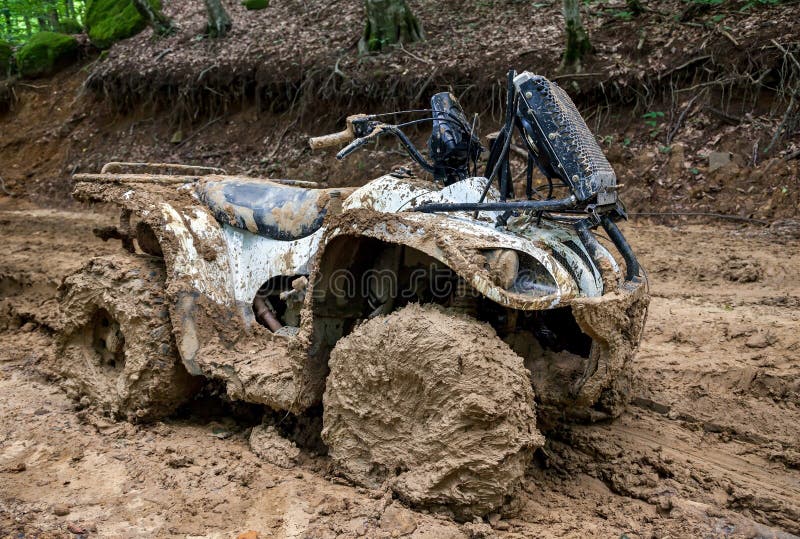 Quad bike in mountainous area on impenetrable road in dense forest. The ATV is very much covered with mud. Quad bike in mountainous area on impenetrable road in dense forest. The ATV is very much covered with mud