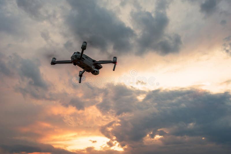 Quadcopter do zang?o com voo da c?mara digital no por do sol foto de stock Quadcopter do zang?o com voo da c?mara digital no por do sol foto de stock