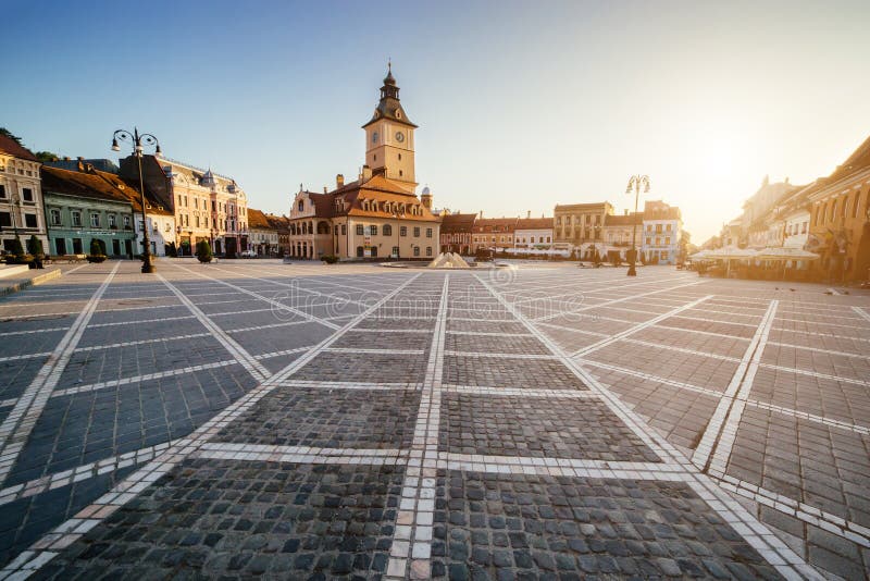 Quadrato centrale della città (Piata Sfatului) con la vista di alba di mattina della torre del corridoio del consiglio comunale, fotografia stock libera da diritti Quadrato centrale della città (Piata Sfatului) con la vista di alba di mattina della torre del corridoio del consiglio comunale, fotografia stock libera da diritti