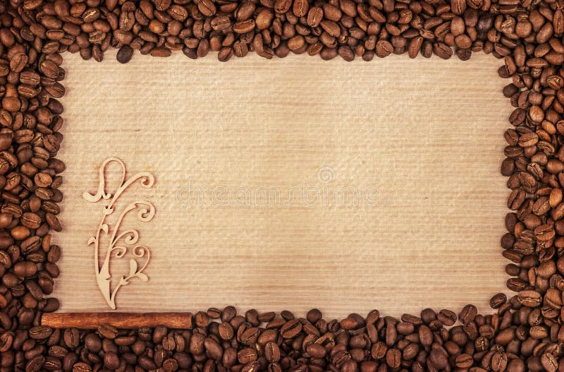 Grunge frame made of coffee beans on birch wood background with scrap flower on cinnamon stick. Grunge frame made of coffee beans on birch wood background with scrap flower on cinnamon stick.