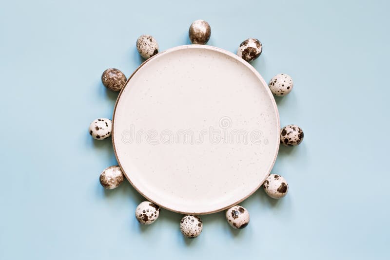 Quail eggs and white rustic plate on pastel blue background. Minimal Easter composition royalty free stock photography