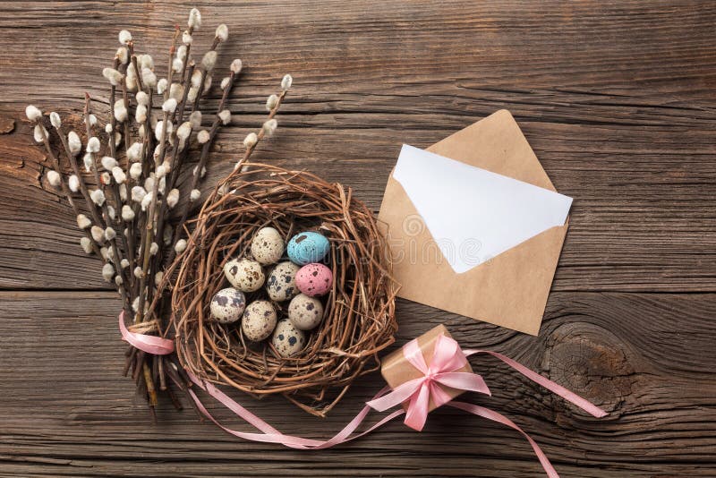 Quails eggs in nest, gift box and flowers. Easter greeting card. Top view