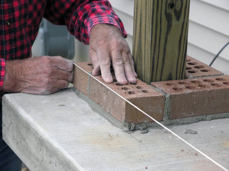 Skillful master bricklayer uses level line to ensure quality. Skillful master bricklayer uses level line to ensure quality