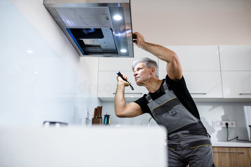 Always Quality Service. Aged Repairman in Uniform Working, Examining