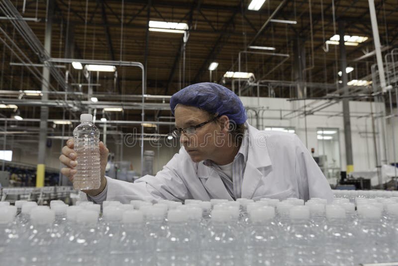 Qualitätskontrollarbeitskraft, die Tafelwasser in Abfüllbetrieb überprüft lizenzfreies stockbild Qualitätskontrollarbeitskraft, die Tafelwasser in Abfüllbetrieb überprüft lizenzfreies stockbild
