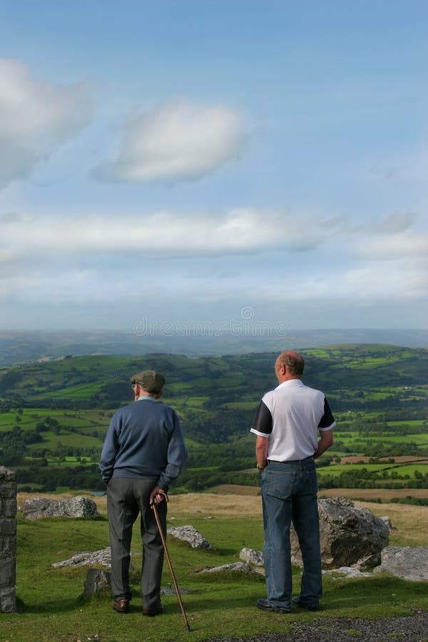 Two elderly men, one with a walking stick, standing and gazing at a rural landscape. Set in the Brecon Beacons National Park, Wales, United Kingdom. Two elderly men, one with a walking stick, standing and gazing at a rural landscape. Set in the Brecon Beacons National Park, Wales, United Kingdom.