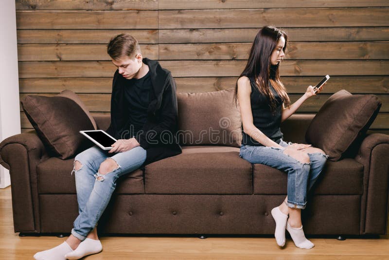 Quarreled couple looking into their digital gadgets