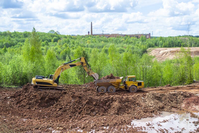 In a Quarry, a Yellow Excavator with a Large Bucket Loads Clay into a  Truck. Against the Background of an Old Red Brick Factory Stock Image -  Image of excavator, clay: 189392629