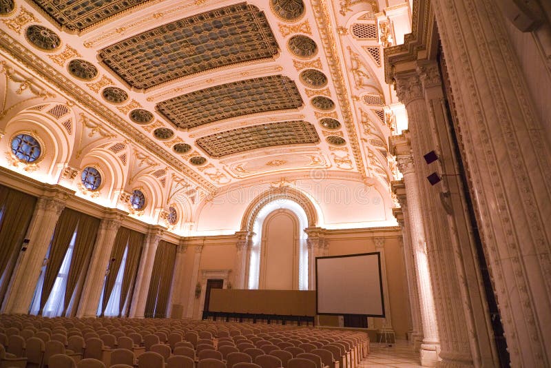 A picture of the interiors of a room in a palace, with chairs set up for a seminar. A picture of the interiors of a room in a palace, with chairs set up for a seminar.