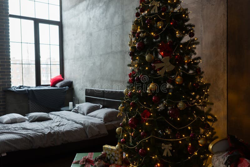 Quarto à moda com cama moderna e grande árvore de Natal com a fotos de stock Quarto à moda com cama moderna e grande árvore de Natal com a fotos de stock