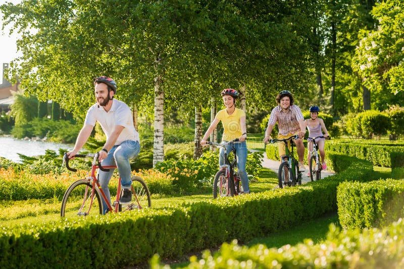 Quatre amis gais faisant un cycle dehors photo libre de droits Quatre amis gais faisant un cycle dehors photo libre de droits
