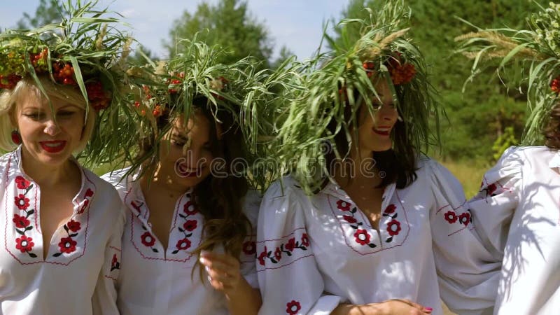 Quatre femmes en costumes ethniques marchant dehors le jour du soleil