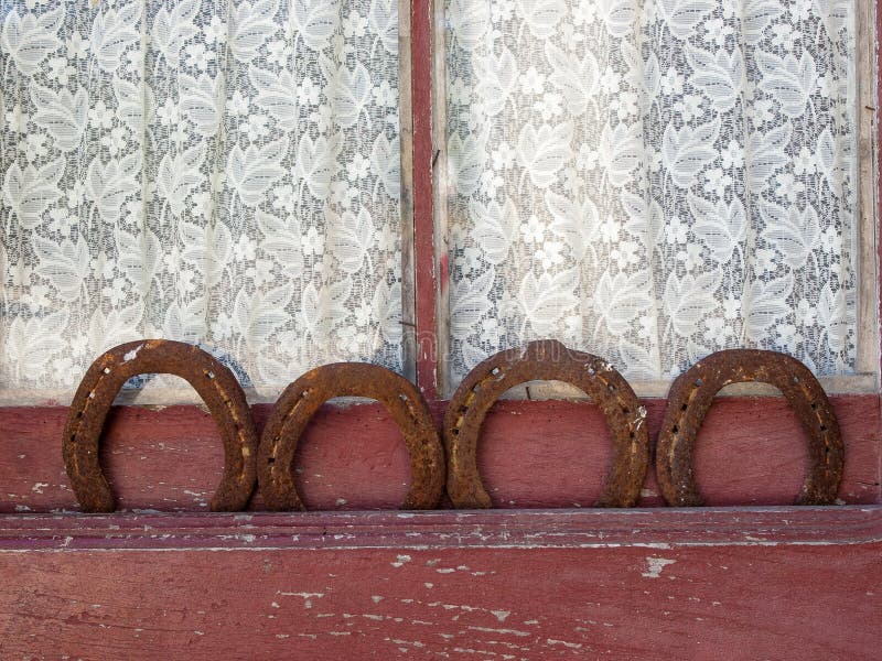Quatre fers à cheval dans une vieille fenêtre avec le rideau