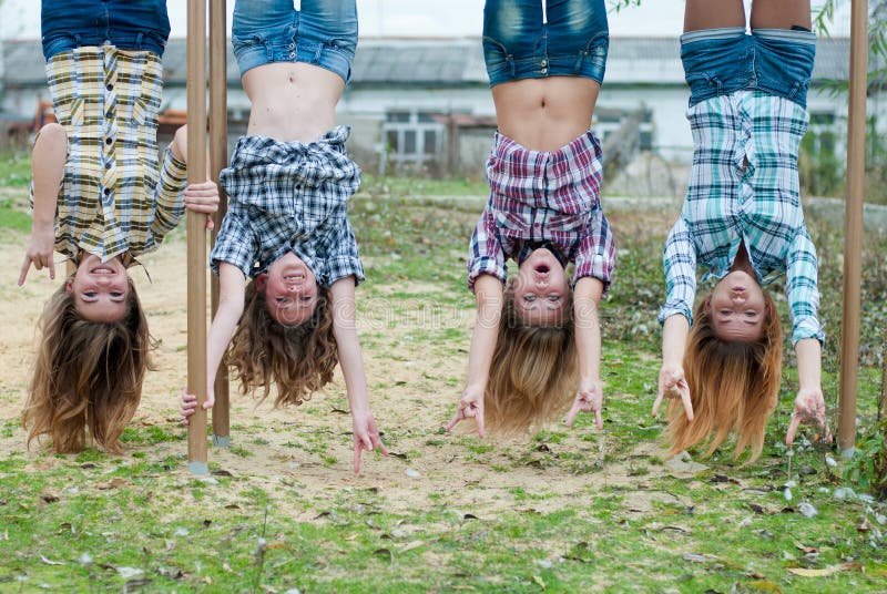 Quatre jeunes filles s'arrêtant upside-down en stationnement image libre de droits Quatre jeunes filles s'arrêtant upside-down en stationnement image libre de droits