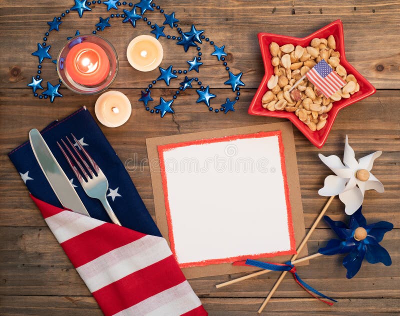 Fourth of July Table Place Setting with red, white and blue decorations and blank card with copy space. It`s a horizontal crop with flat layout on rustic wood table. Fourth of July Table Place Setting with red, white and blue decorations and blank card with copy space. It`s a horizontal crop with flat layout on rustic wood table.