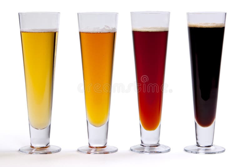 Four beers in glasses arranged in color from light gold to dark on light background. Four beers in glasses arranged in color from light gold to dark on light background.