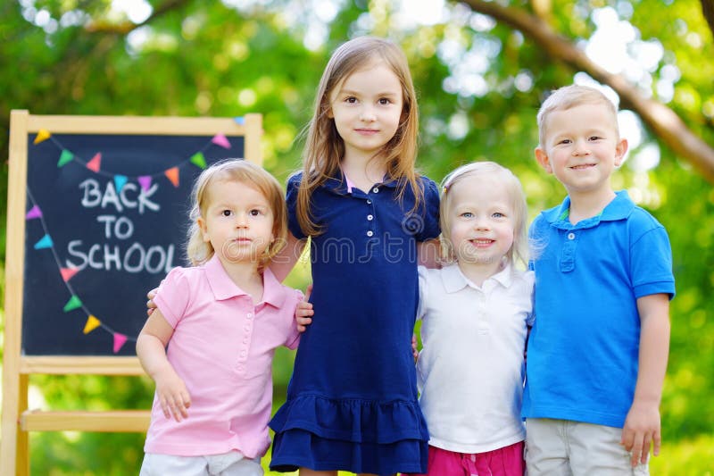Quatro crianças adoráveis estão indo para trás à escola fotografia de stock Quatro crianças adoráveis estão indo para trás à escola fotografia de stock