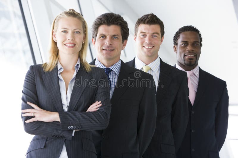 Quatro empresários que estão no sorriso do corredor foto de stock Quatro empresários que estão no sorriso do corredor foto de stock