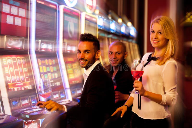 Quatro jovens que jogam slots machines no casino imagens de stock Quatro jovens que jogam slots machines no casino imagens de stock