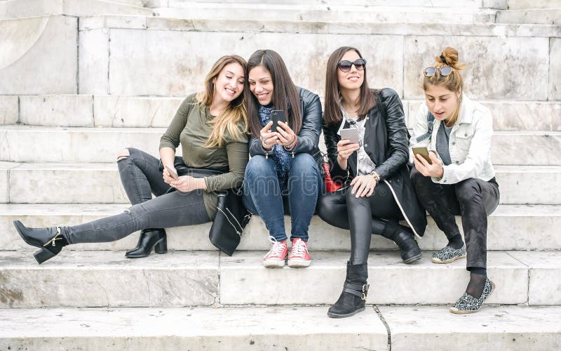Quatro meios sociais de observação felizes do Internet das namoradas no smartp foto de stock Quatro meios sociais de observação felizes do Internet das namoradas no smartp foto de stock