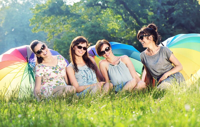 Quattro amiche graziose che tengono gli ombrelli variopinti immagini stock