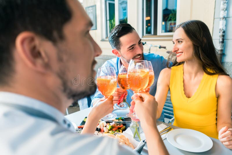 Quattro amici che tostano insieme ad un freddo che rinfresca bevanda alcolica fotografia stock Quattro amici che tostano insieme ad un freddo che rinfresca bevanda alcolica fotografia stock