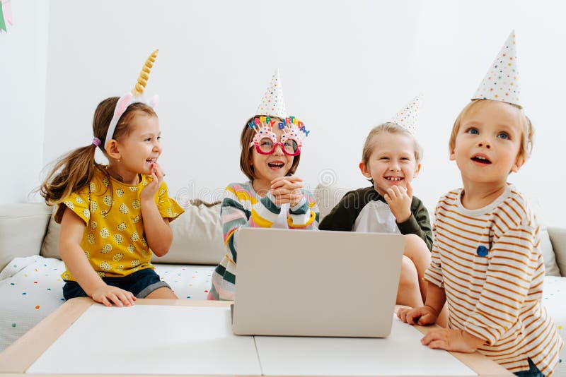 Quattro bambini che fanno festa online in quarantena a casa fotografia stock libera da diritti
