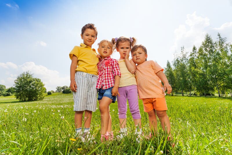 Quattro bambini che stanno vicino ad a vicenda in prato fotografia stock libera da diritti Quattro bambini che stanno vicino ad a vicenda in prato fotografia stock libera da diritti