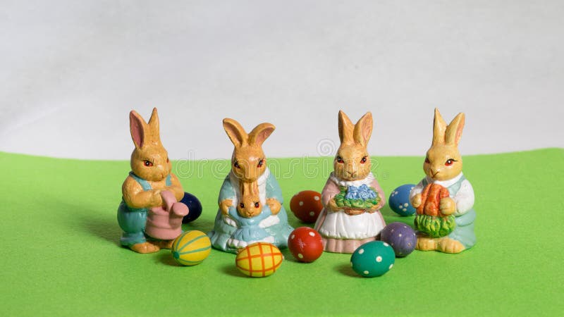Quattro coniglietti di pasqua ` s del bambino con le uova sul prato verde immagine stock libera da diritti Quattro coniglietti di pasqua ` s del bambino con le uova sul prato verde immagine stock libera da diritti
