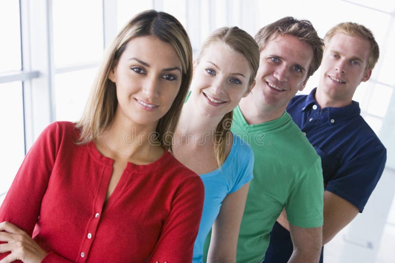 Quattro genti che si levano in piedi nel sorridere del corridoio immagine stock libera da diritti