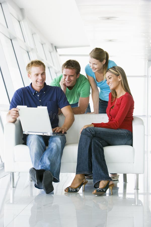 Quattro genti in ingresso che esamina sorridere del computer portatile immagine stock