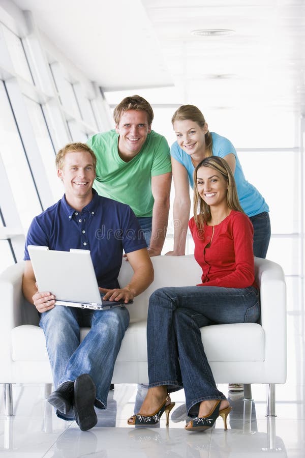 Quattro genti in ingresso con sorridere del computer portatile immagine stock libera da diritti