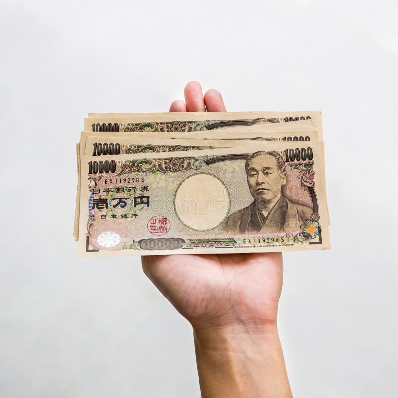Hand holding a 10000 yen banknote for trading, exchange, or doing business and tourism. On white background. Hand holding a 10000 yen banknote for trading, exchange, or doing business and tourism. On white background