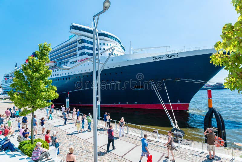 Hamburg, Germany - August 19, 2014: Queen Mary 2, the luxurious Cunard Liner is visiting Hamburg for 10 years which is celebrated during a visit of the ship on August 19, 2014 in Hamburg, Germany. While the cruise liner is docked at the cruise terminal in Hamburg, waiting for its passengers to board for the forthcoming New York trip, many people pay the ship a visit appreciating the elegance and s. Hamburg, Germany - August 19, 2014: Queen Mary 2, the luxurious Cunard Liner is visiting Hamburg for 10 years which is celebrated during a visit of the ship on August 19, 2014 in Hamburg, Germany. While the cruise liner is docked at the cruise terminal in Hamburg, waiting for its passengers to board for the forthcoming New York trip, many people pay the ship a visit appreciating the elegance and s