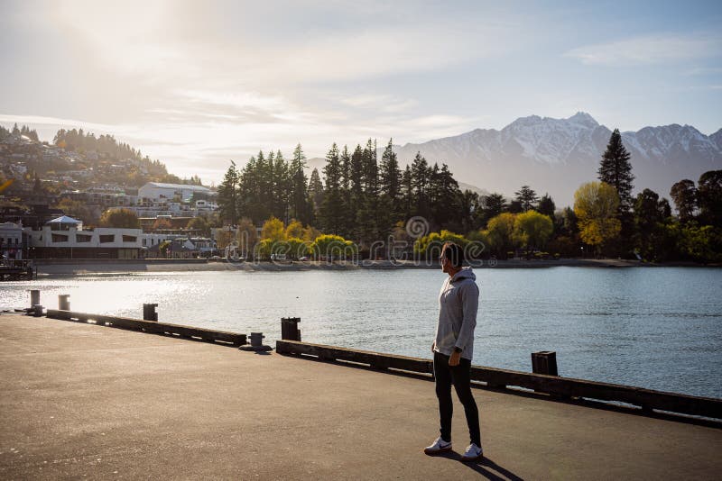 Queenstown, New Zealand, October 6, 2019: Beautiful image of a boy watching the orange sunrise among the snowy mountains