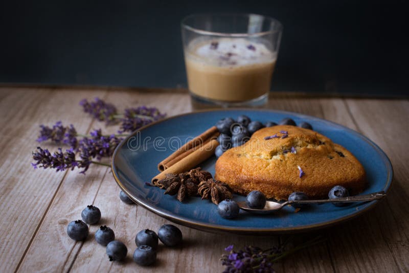 Moody dark food photo with a muffin and cranberries on a blue plate, nespresso capsules and a coffee cup in the background. Moody dark food photo with a muffin and cranberries on a blue plate, nespresso capsules and a coffee cup in the background