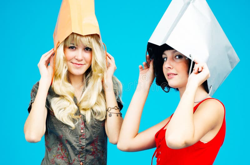 Two girls wear shopping bags as hats. Concept, love to shop. Two girls wear shopping bags as hats. Concept, love to shop