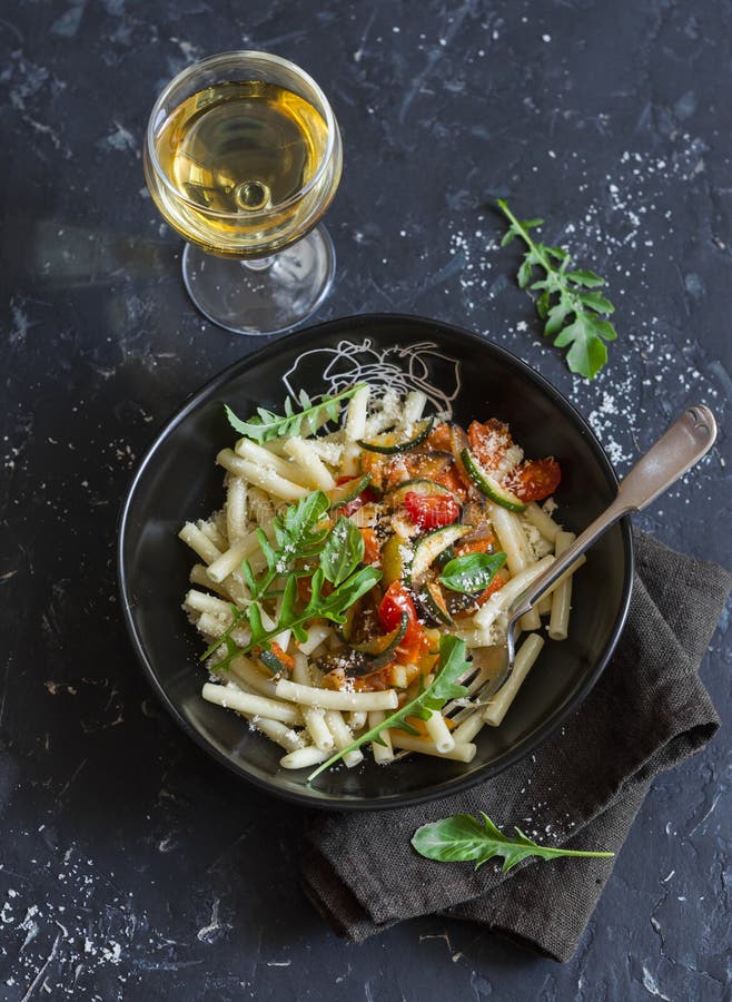 Quick ratatouille pasta and a glass of white wine on dark background, top view. stock images Quick ratatouille pasta and a glass of white wine on dark background, top view. stock images