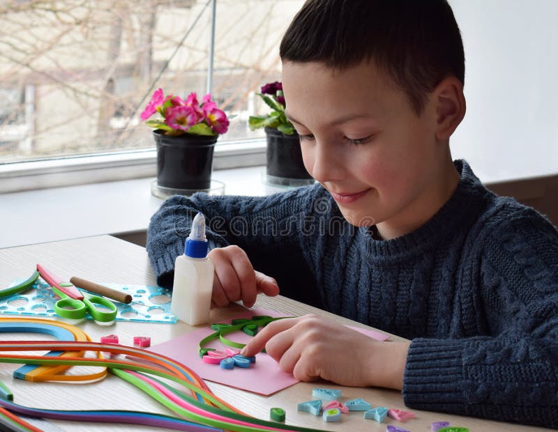 Quillingstechniek Jongen die decoratie of groetkaart maken Document stroken, bloem, schaar Met de hand gemaakte ambachten op vaka stock afbeelding Quillingstechniek Jongen die decoratie of groetkaart maken Document stroken, bloem, schaar Met de hand gemaakte ambachten op vaka stock afbeelding