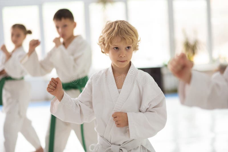 Quimono branco vestindo do menino que repete movimentos do aikido foto de stock Quimono branco vestindo do menino que repete movimentos do aikido foto de stock