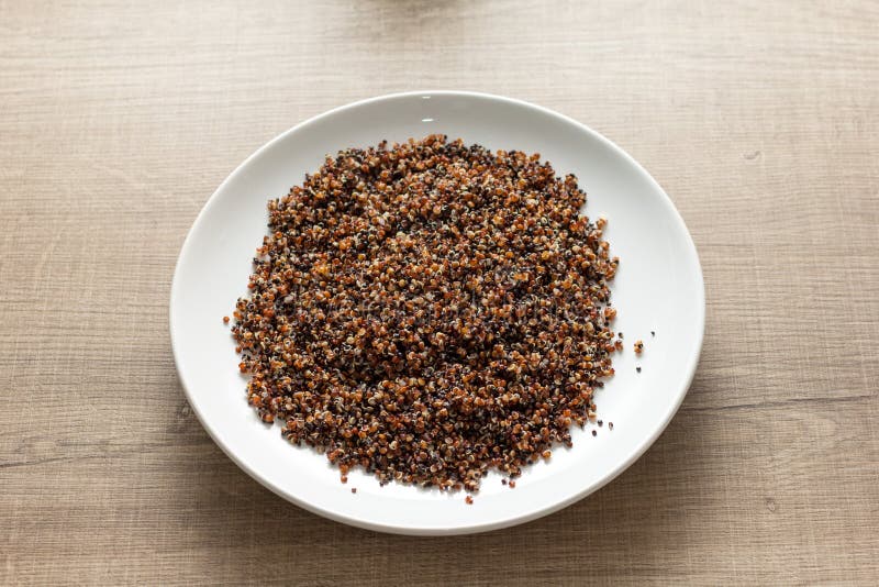 Quinoa vermelho e preto cozinhado misturado Refeição no prato branco e de madeira imagens de stock royalty free Quinoa vermelho e preto cozinhado misturado Refeição no prato branco e de madeira imagens de stock royalty free